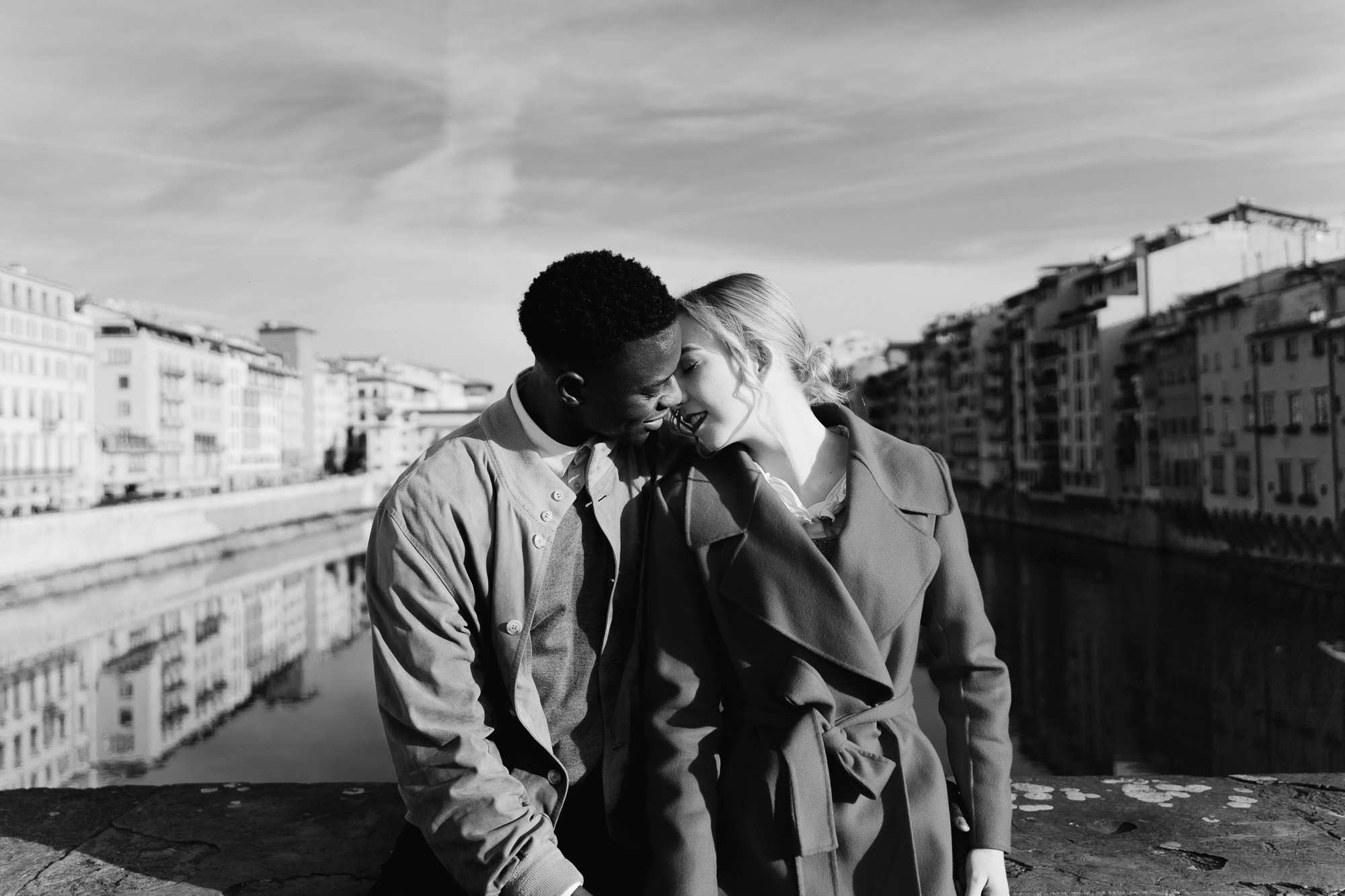 B&W wide shot of the couple on a bridge with the Florence skyline in the distance