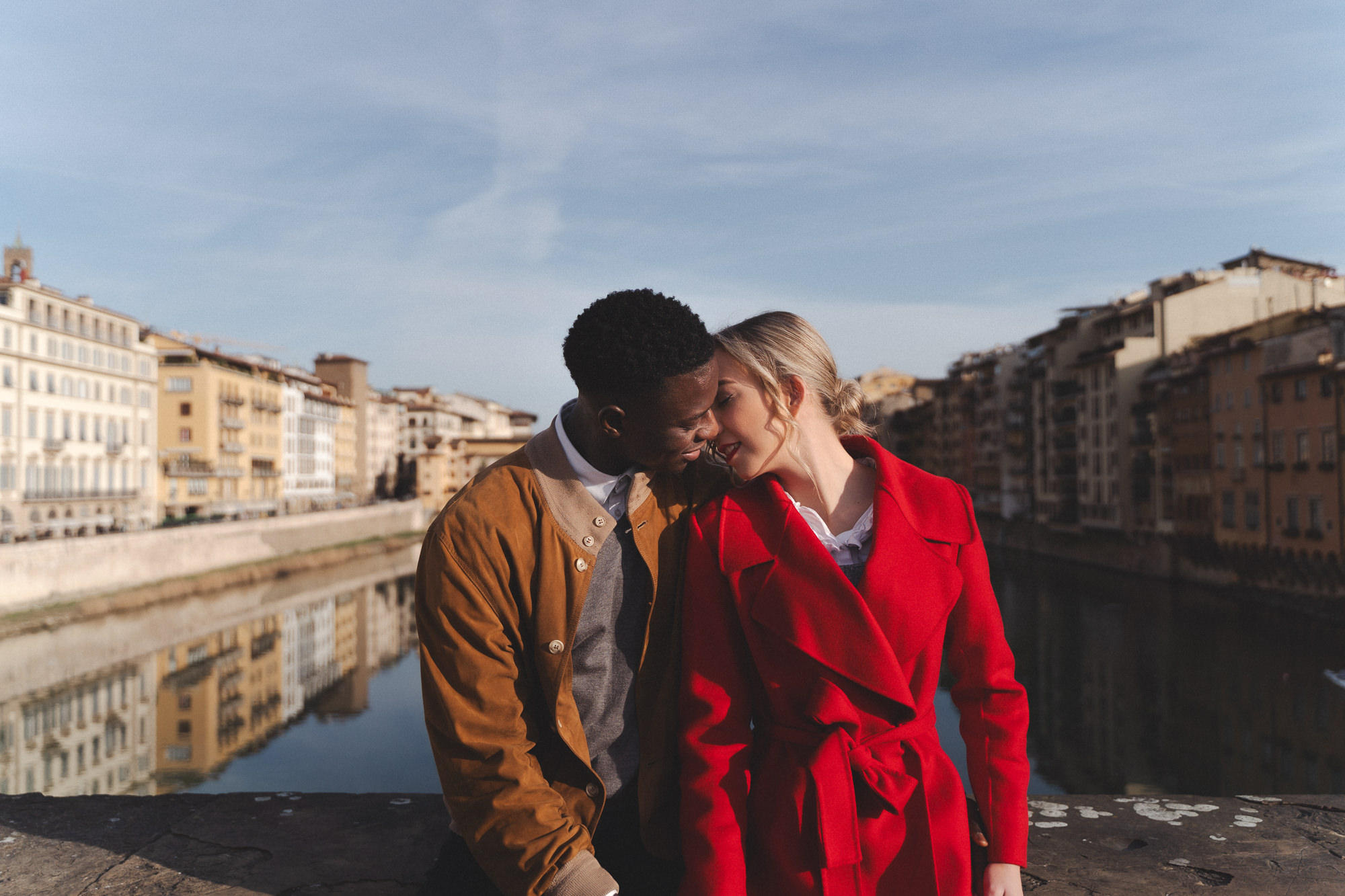 Color shot of the couple on a bridge overlooking the Arno during golden hour. Ponte Vecchio