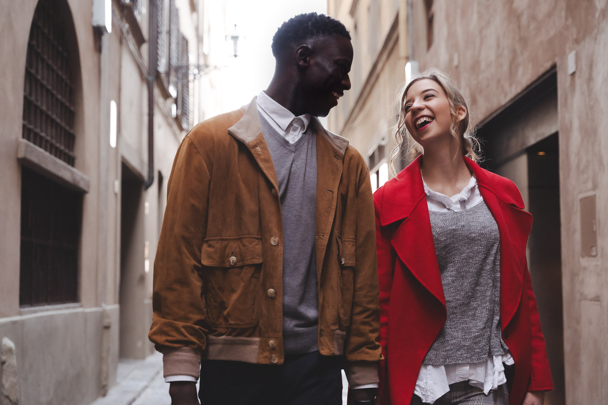 Couple walking and laughing in a narrow historic street.