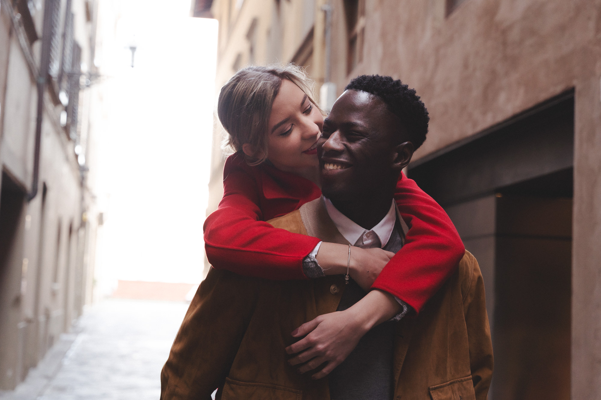 Couple laughing during a piggyback ride in the streets of Florence