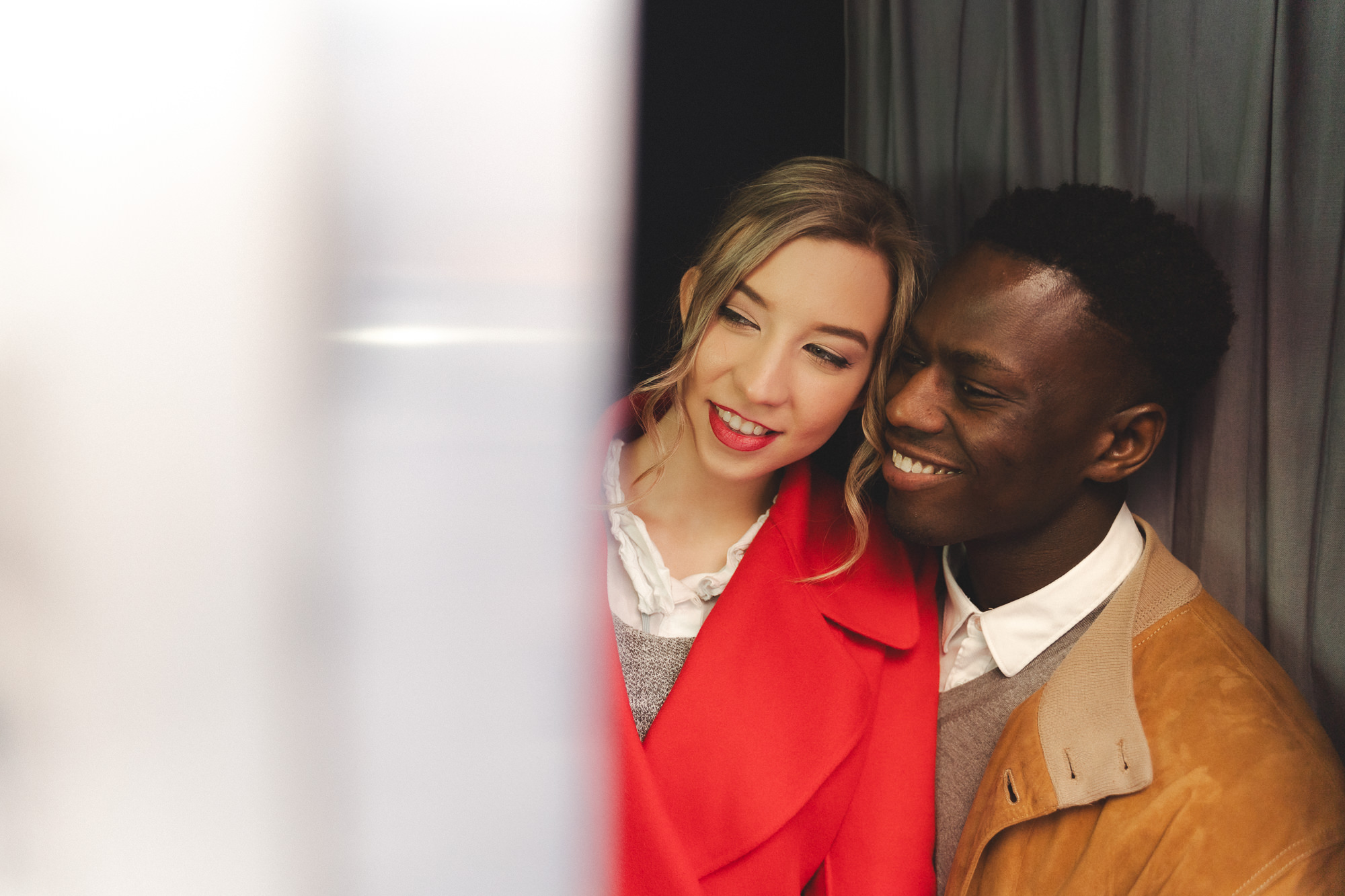 Couple looking out from the vintage photo booth, smiling