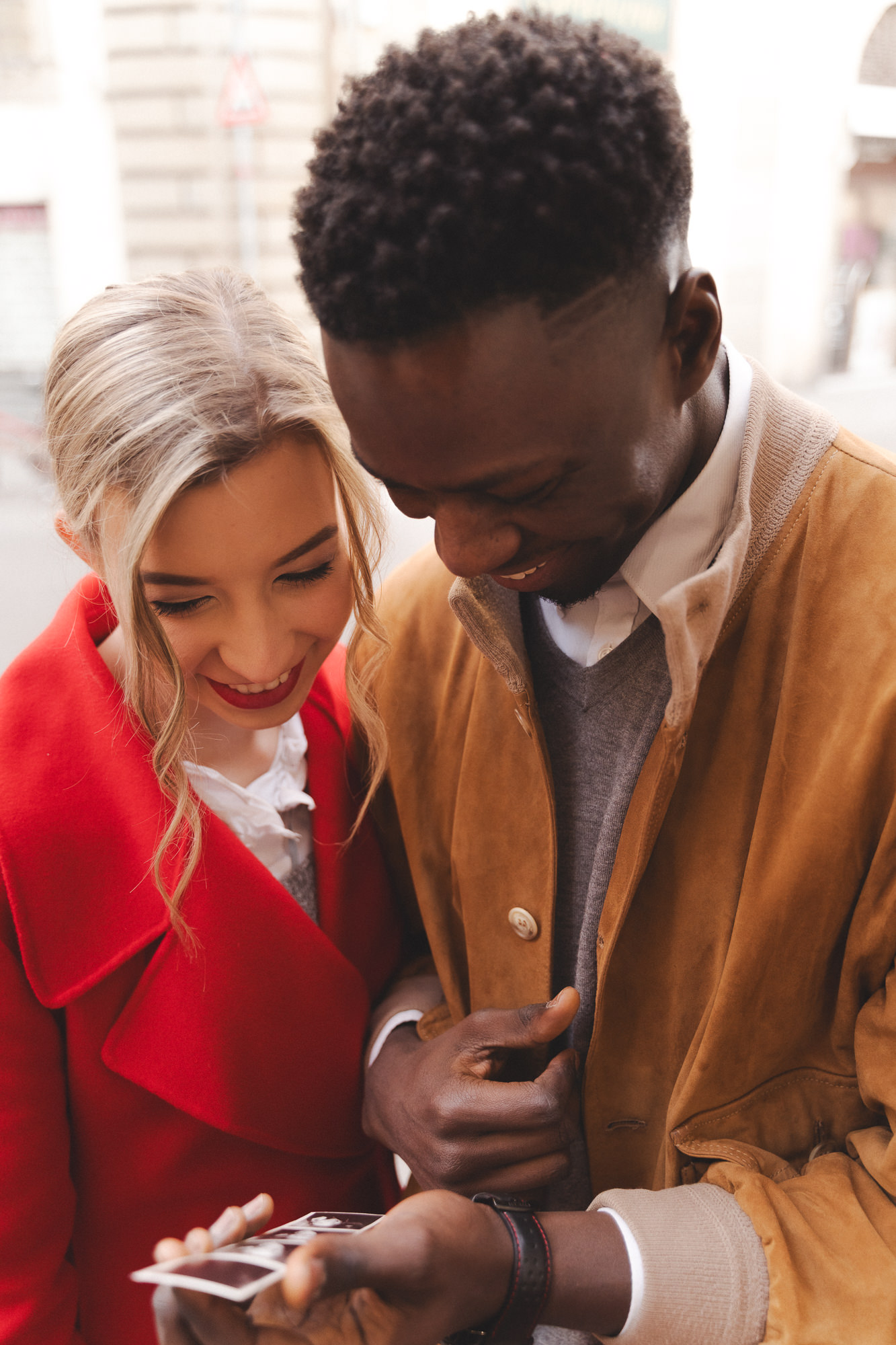 Couple walking and looking at their printed photos in the street